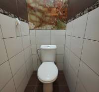 A toilet with light tiles and a decorative panel in a 3-room apartment.
