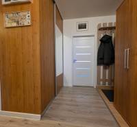 A hallway in a 3-room apartment with wooden decor and a coat rack wall.