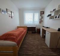 A simply furnished bedroom or study in a 3-room apartment with a bed and a desk.