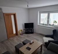 Living room in a family house with wood-patterned flooring, a television, and seating.
