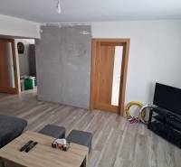 Living room with wood-patterned flooring, a sofa set, and a television in a family house.