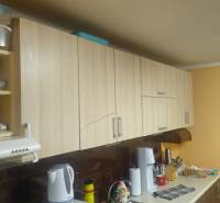 A kitchen in a family house with wooden cabinets and accessories on the kitchen counter.