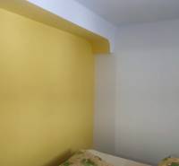 Yellow wall in a room of a family house with a pillow on the right.