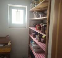 Food storage in the pantry of a family house with shelves full of preserves and cartons.