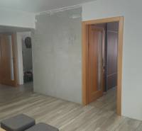 Interior of a family house with a wooden decor floor, a television, and open doors.