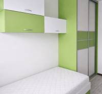 Single bed with storage cabinets in a 3-room apartment, floor with wooden decor.