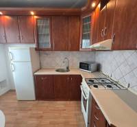 A kitchen in a 3-room apartment with dark cabinets and a wood-patterned floor.