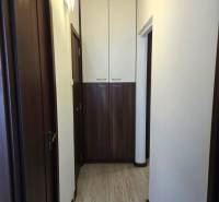 A narrow hallway in a 3-room apartment with a wooden decor floor and storage cabinets.