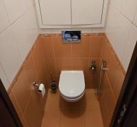 A toilet with tiles and a white cabinet in a 3-room apartment.