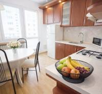 A kitchen in a 3-room apartment with a wooden decor floor and fruit on the table.