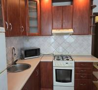 A kitchen in a 3-room apartment with a wood-decor floor and wooden cabinets.