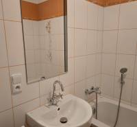 A bathroom in a 3-room apartment with a sink, bathtub, and orange tiles.