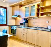 A kitchen with wooden decor, appliances, and a dining table in a two-room apartment.