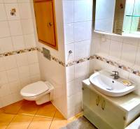 A bathroom in a 2-room apartment with ceramic tiles and light furniture.