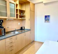 A kitchen in a 2-room apartment with a wooden decor floor and a wooden kitchen unit.