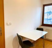 Dining area with a white table and chairs in a 2-room apartment, floor with wood decor.