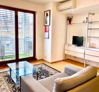 Living room in a 2-room apartment with an armchair, a glass table, and a floor with a wood decor.