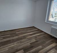 A room in a 3-room apartment with a wooden decor floor and a window with a view.