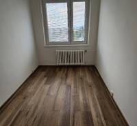 An empty room in a 3-room apartment with a wooden decor floor and a radiator.