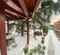 A snowy terrace at a family house on Rampová Street in Košice with a gazebo and greenery.