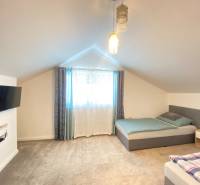 Bedroom in a family house with two beds, a television, and carpeted flooring.