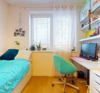 A room with a bed, a desk, shelves, and a floor with a wooden decor in a 4-room apartment.