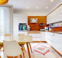 Kitchen in a 4-room apartment, wooden decor flooring, dining table, white cabinets.