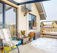 Snow-covered terrace of a 4-room apartment with a chair, plants, and a sofa.