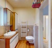 Bathroom with a shower, wood-patterned floor, toilet, and sink in a 4-room apartment.