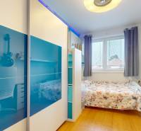 A room in a 4-room apartment with a bed, a desk, and a floor with a wooden decor.