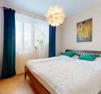 A bedroom in a 4-room apartment with a large bed, a chandelier, and a floor with a wooden decor.