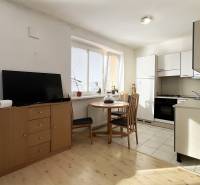 A kitchen with a dining table and a wooden decor floor in a studio apartment.