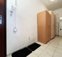 Hallway in a one-room apartment with white walls, tiles, and cabinets.
