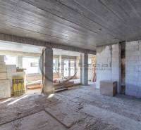The interior of a building under construction with building materials and a concrete ceiling.