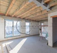 The interior of an unfinished building with a wooden ceiling and large windows.