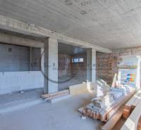 The interior of a building under construction with an uneven brick wall and construction materials on the floor.