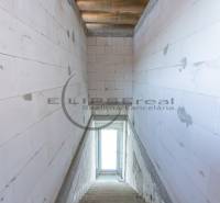 A view of a staircase in a building with concrete walls and a window at the end.