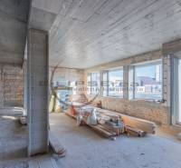 Interior of a building with brick walls, large windows, and construction materials.