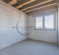 An empty room with white walls, a wooden ceiling, and a large window in a building.