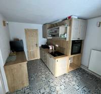 A kitchen in a family house with tiles and wooden cabinets, equipped with an oven and wood.