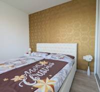 A bedroom with Christmas bedding, wallpaper, and flowers in a 3-room apartment.