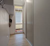 A hallway with a wooden decor floor and storage cabinets in a 3-room apartment.