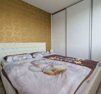 Bedroom in a 3-room apartment with wallpaper and a built-in wardrobe, floor with wood decor.