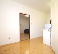 A room with a wood-decor floor in a 2-room apartment with a radiator and a microwave.