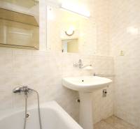 Bathroom tiles and sink in light colors in a 2-room apartment.