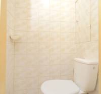 A bathroom tiled with light tiles in a 2-room apartment.
