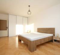 Bedroom in a two-room apartment with a wooden decor floor, bed, and wardrobe.