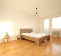 Bright bedroom with a bed and a chair, wooden decor flooring, 2-room apartment.