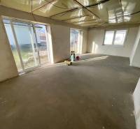 A spacious room in a family house with a raw concrete floor, large windows provide plenty of light.