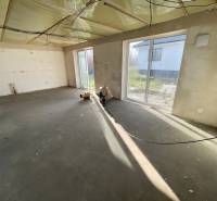 An empty room with large windows in a family house, without floor covering.